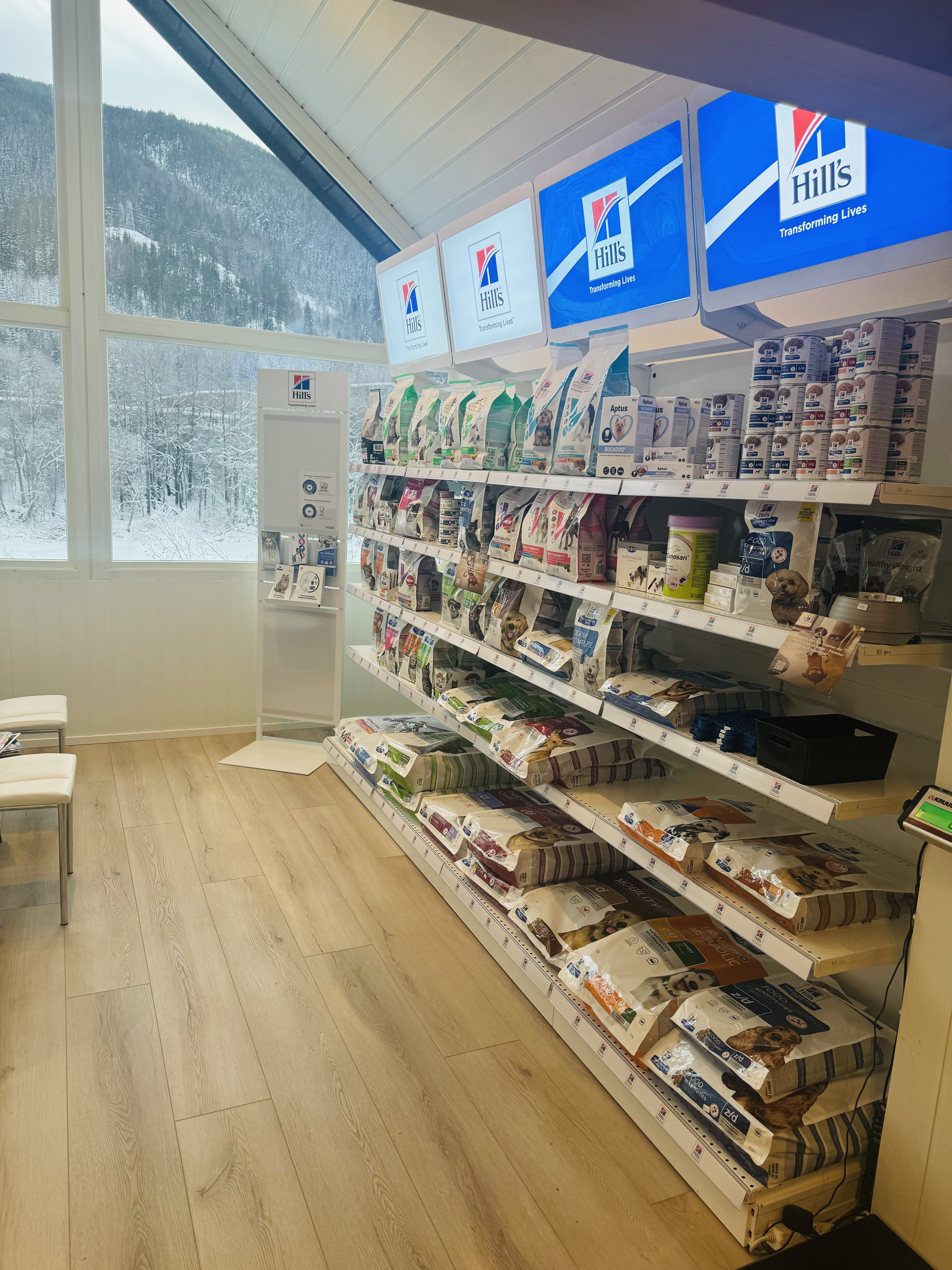 Hyller med fôr inne i klinikken, store skilt med Hills logo på toppen